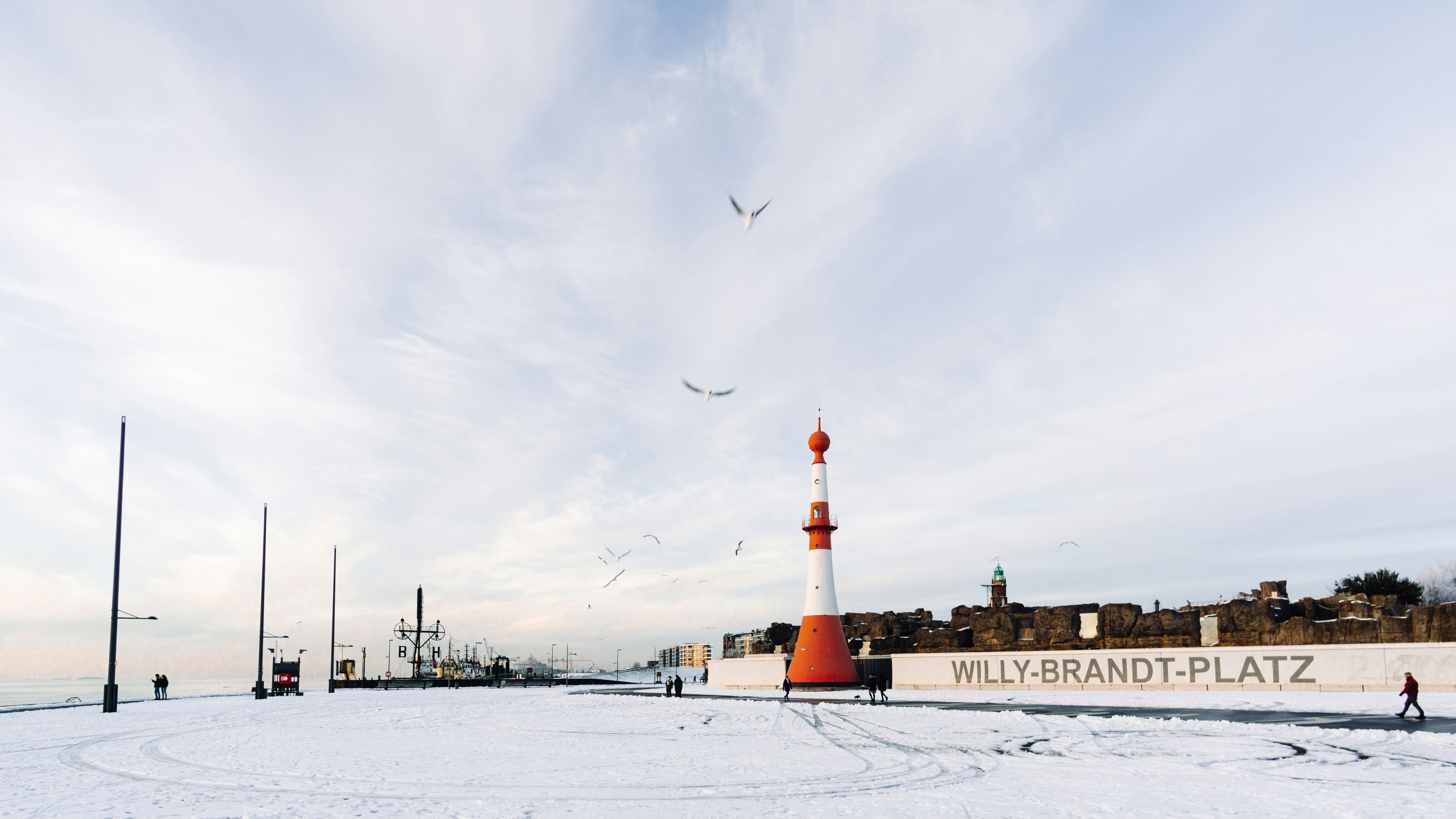 brown and white lighthouse on snow covered ground under cloudy sky during daytime